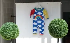 Шарен бебешки гащеризон с дъга, окачен на закачалка